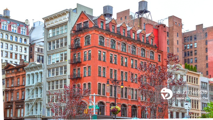 Colorful brick buildings, with windows and fire stairs. Water deposits on rooftops. NYC, USA