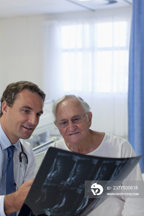 Male doctor showing x-rays to senior patient in hospital room