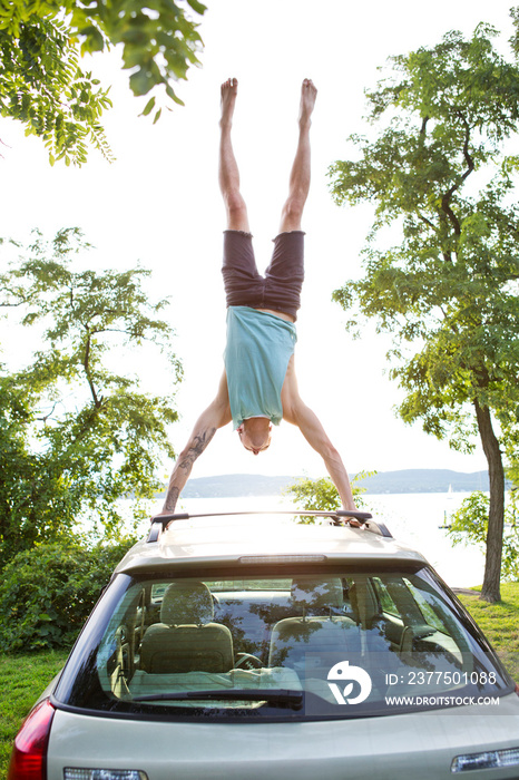 Man doing handstand on roof of car