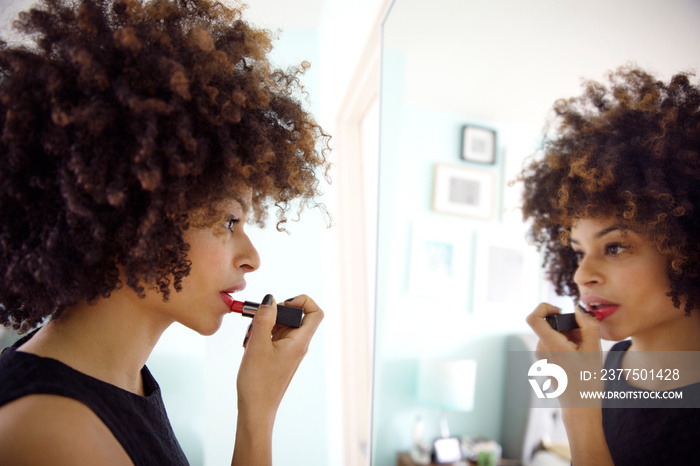 Young woman applying red lipstick