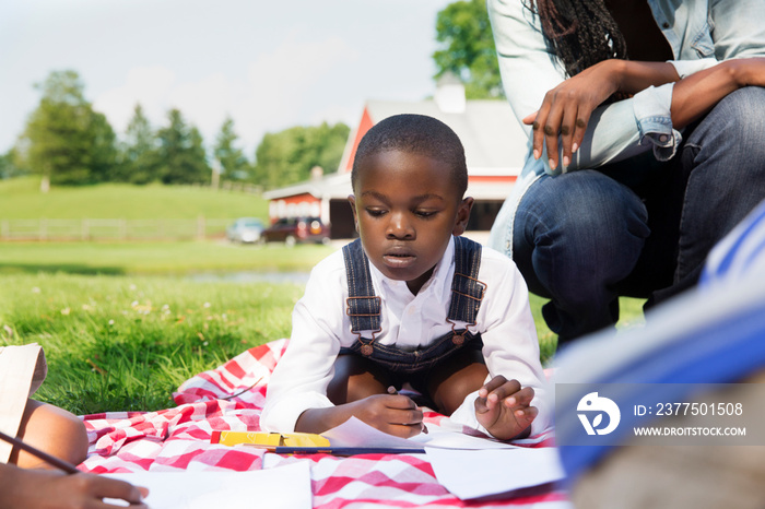 Boy (4-5) writing in note pad on field trip