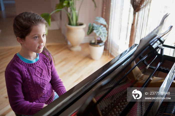 Girl (8-9) playing piano in living room