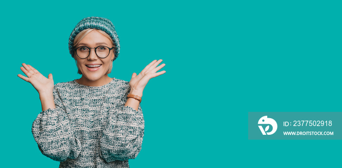 Portrait of a lovely young blonde woman laughing while showing her hands up looking at camera dresse