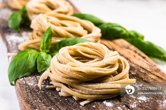 Raw uncooked italian tagliatelle pasta on wooden board