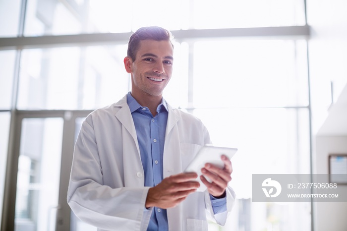 Portrait of doctor using digital tablet in hospital corridor