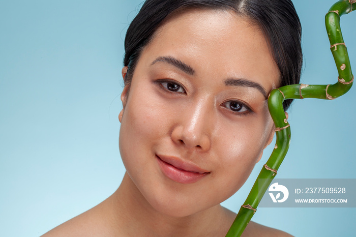 Studio portrait of woman with green bamboo twig