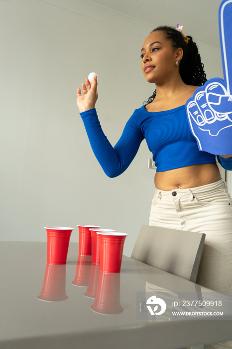 Young woman playing beer pong at home party