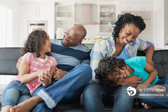 Playful family of four sitting on sofa at home