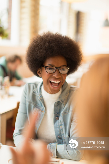 Happy young woman with afro laughing in cafe