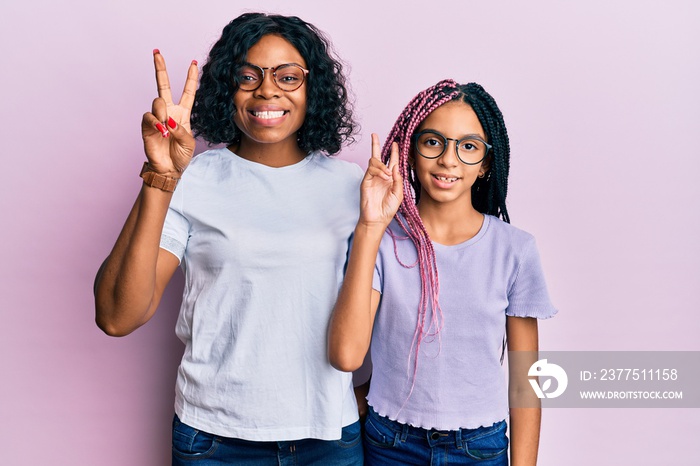 Beautiful african american mother and daughter wearing casual clothes and glasses smiling looking to