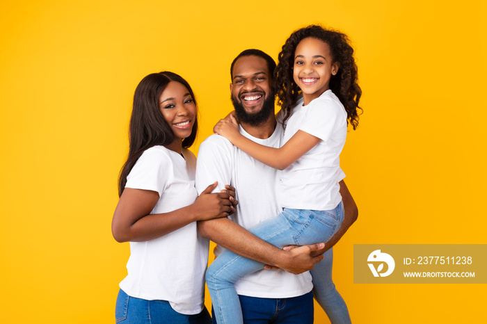 Happy black man posing with wife and smiling cute daughter