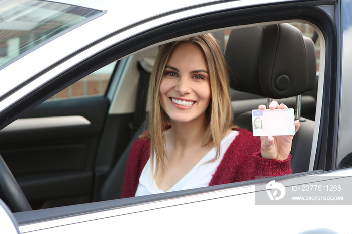 Junge Frau zeigt lachend ihren Führerschein