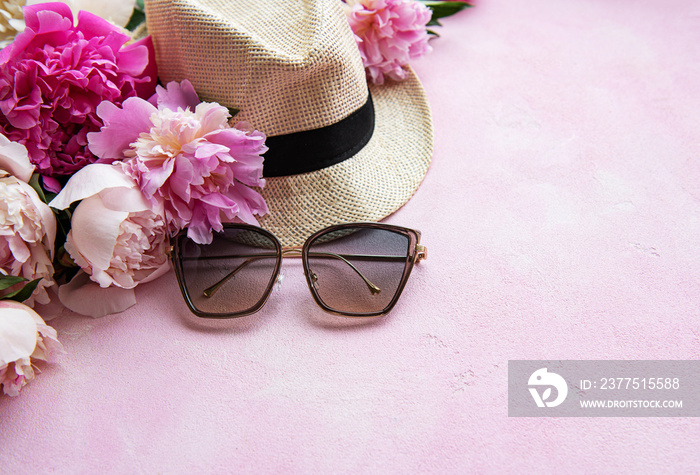 Pink peonies and hat on a pink concrete background