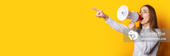 Young woman in a white shirt makes an announcement in a megaphone and points a finger on a yellow ba