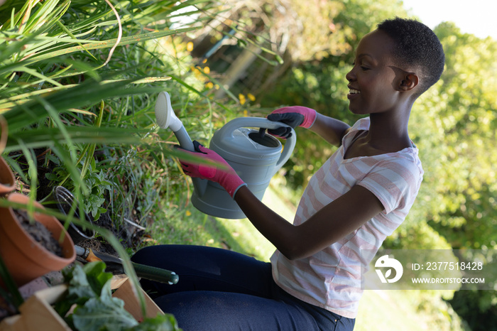 African american woman gardening and smiling on sunny garden terrace