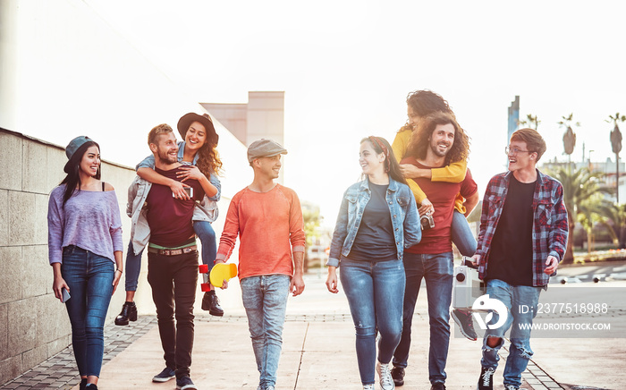 Group of happy friends having fun outdoor - Young people piggybacking while laughing and walking tog