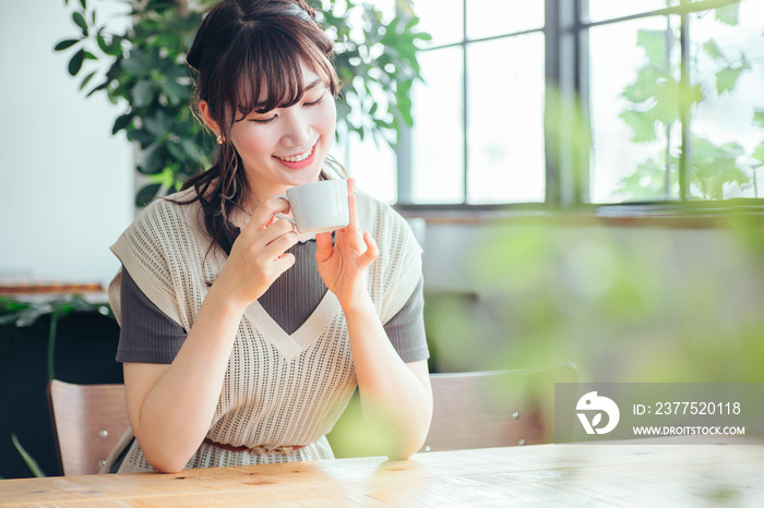 おしゃれ空間でホットドリンクを飲む女性