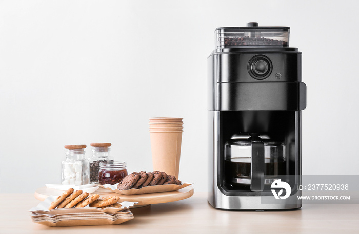 Modern coffee machine and sweets on kitchen table