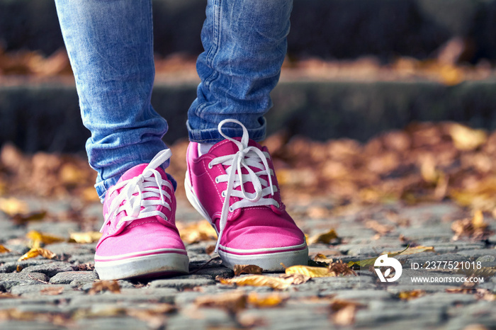 Woman in pink / purple canvas vintage shoes and blue jeans.