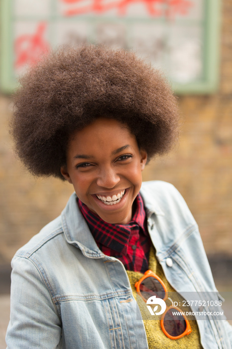 Portrait smiling young woman with afro in denim jacket