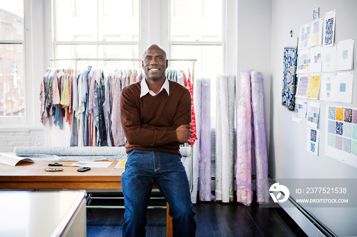 Smiling man sitting on table in design studio