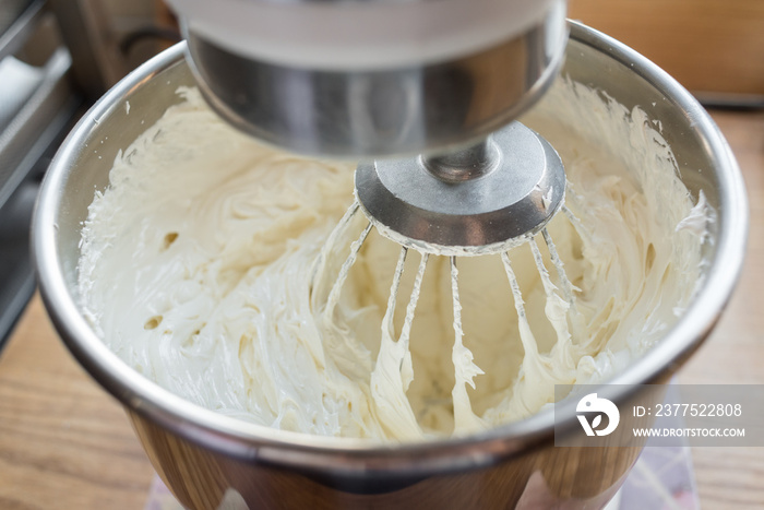用生发的光滑面团制作蛋糕的电动搅拌器特写。正在搅拌的面糊。搅拌白豆