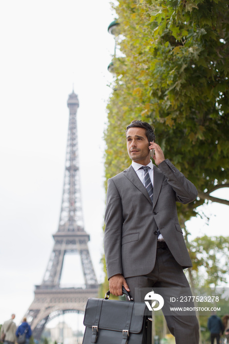 Businessman talking on mobile phone below Eiffel Tower, Paris, France