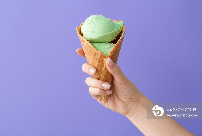 Female hand with sweet ice-cream on color background