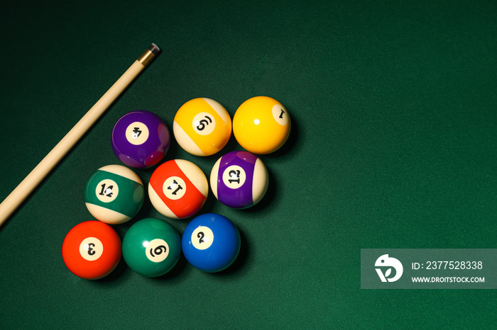 Different billiard balls with cue on green table