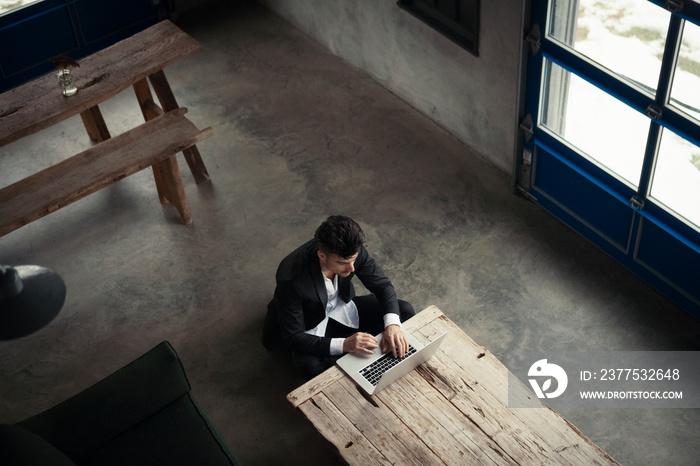 High angle view of man using laptop computer on wooden bench at home