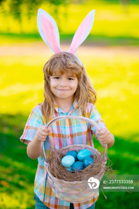复活节快乐。小男孩在草地上猎取复活节彩蛋。户外兔子耳朵里的孩子。东方