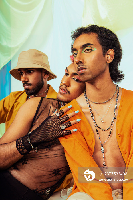 A group of Malaysian Indian men wearing make up posed in a studio setting against a cloth background