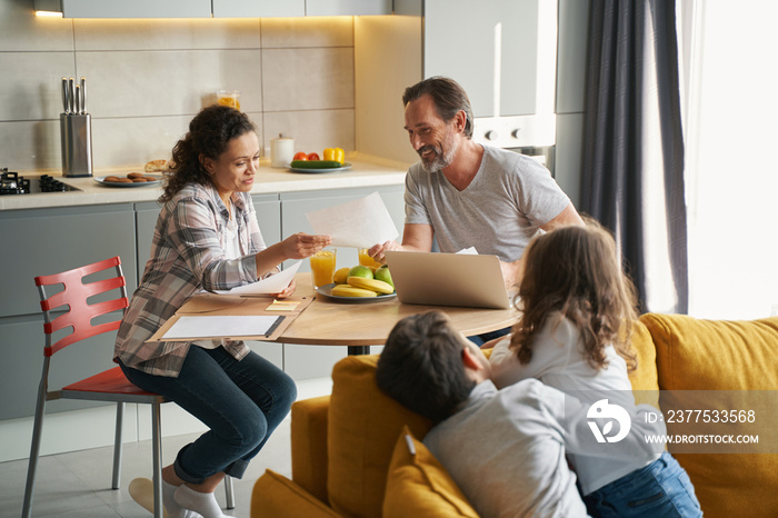 Parents doing taxes in kitchen while children looking