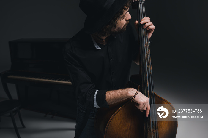 young handsome musician playing contrabass