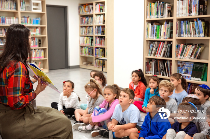 Teacher showing a book to children in a classroom