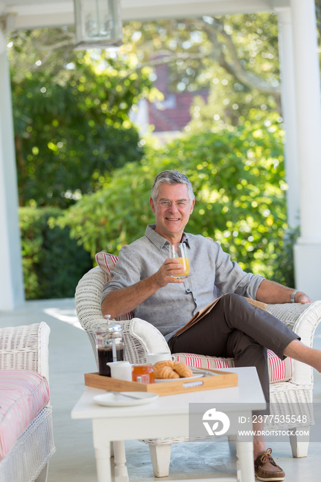 Portrait senior man enjoying breakfast and newspaper on patio
