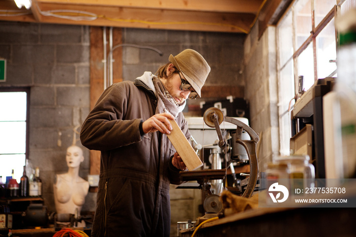 Man shaping wood on machinery at workshop