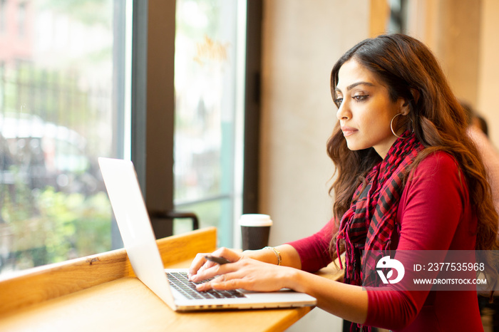 Young businesswoman using laptop in office cafeteria