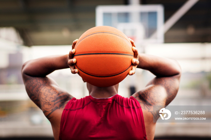 Rear view of man holding basketball behind head