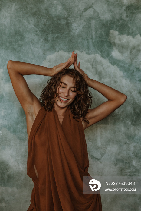 Close up portrait of a non-binary person laughing with hands overhead