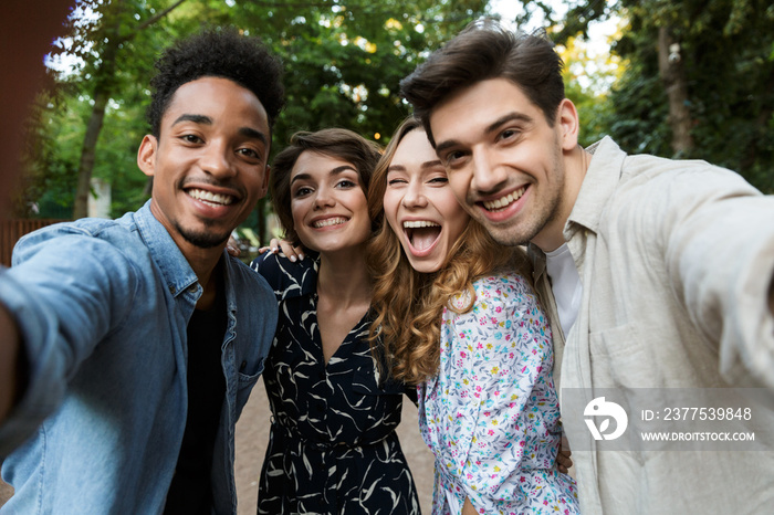 Young group of friends outdoors in park having fun take a selfie by camera.