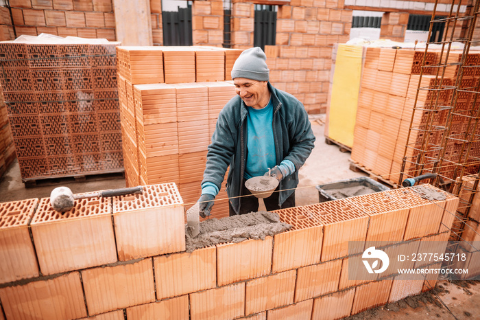 专业工人用砖和砖石细节建造房屋墙壁。施工人员坐着