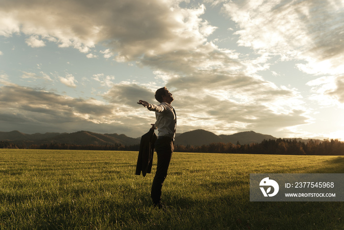 Businessman standing in nature with arms wide open