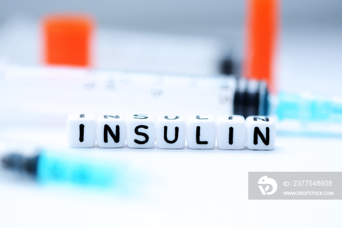 The word insulin spelled with plastic letter beads next to a syringe