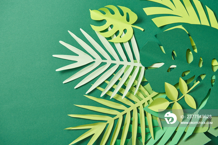 top view of tropical paper cut palm leaves on green background with copy space