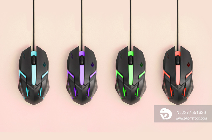 Black computer mouses hang on pastel peach background