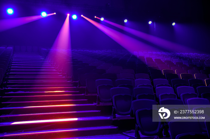 Rows of empty seats in the concert hall in the colored spotlights.