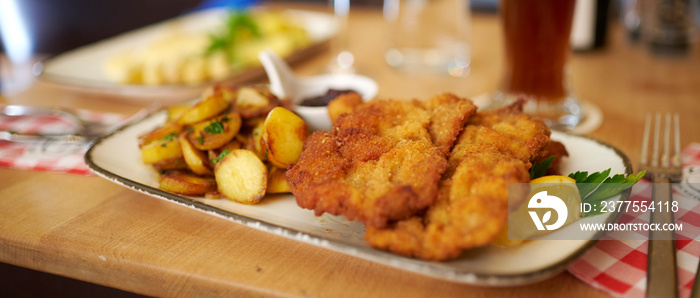 Saftiger Wiener Schnitzel vom Kalb mit wellen Panade und Bratkartoffeln auf schönem Teller