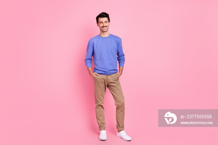 Full length photo of attractive positive young man hold hands pockets isolated on pastel pink color 