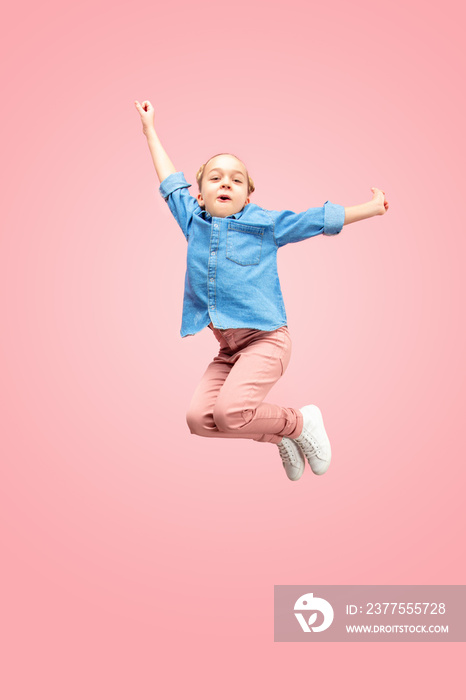 Young happy caucasian teen girl jumping in the air, isolated on pink studio background. Beautiful fe